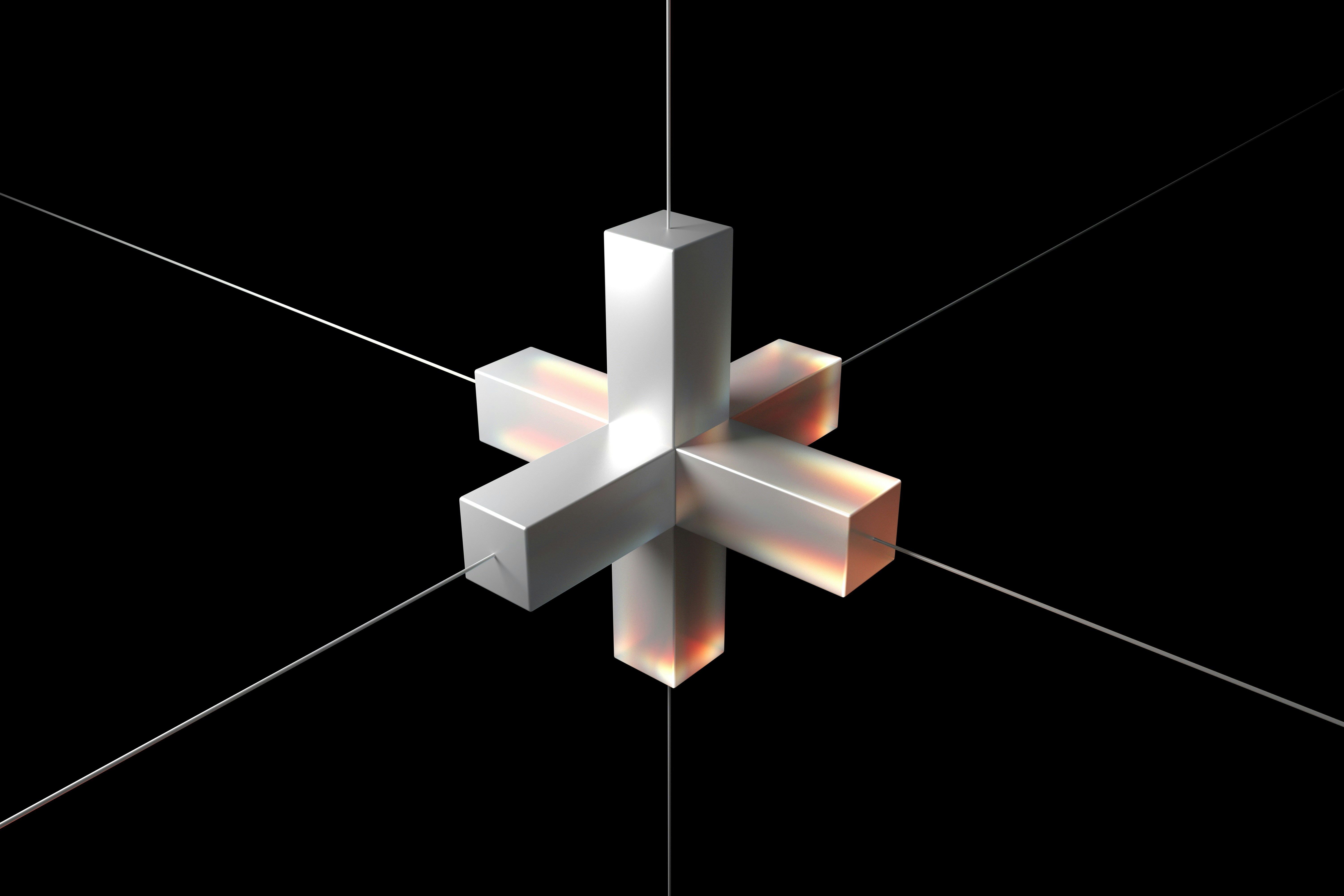 A geometric glass form suspended by thin wires against a black background.